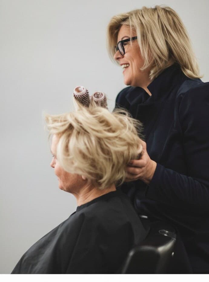 Michaela Gruber föhnt einer Kundin die Haare, Lockenwickler im Deckhaar
